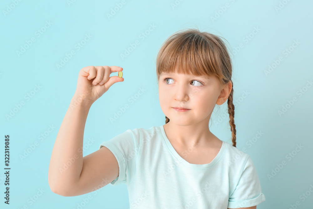 Little girl with fish oil pill on color background Little girl with fish oil pill on color background