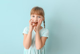 Little girl taking fish oil pill against color background