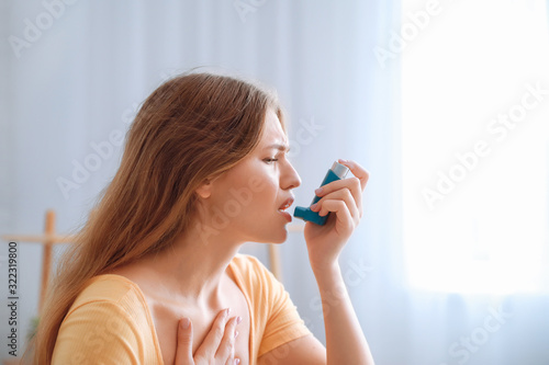 Young woman with inhaler having asthma attack at home