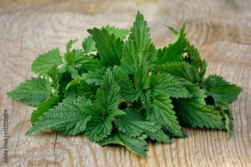 Fresh nettle leaves in a bowl on wooden background close up © Irina