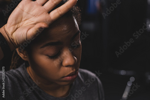 african american girl with closed eyes wiping sweat with hand