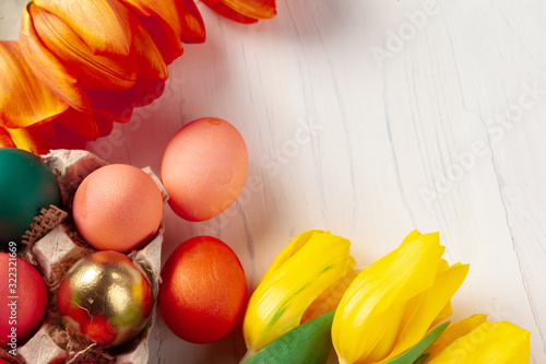 Painted Easter eggs in an eggbox with fresh tulips close up photo