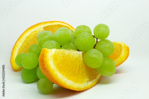 Fresh grapes and orange slices on a white background. Fruit in droplets of water