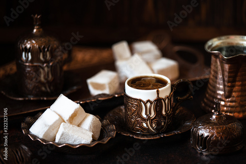 Traditional turkish coffee and turkish delight in traditional oriental copper serving set. Dark vintage background photo