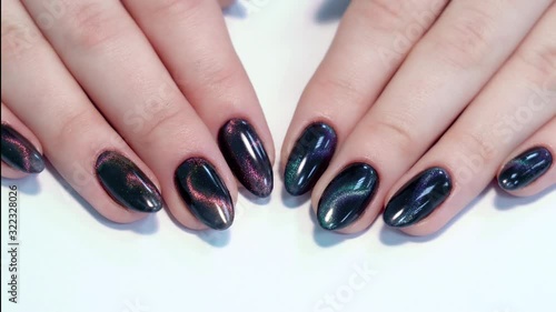 Closeup top view of professional colorful glossy brilliant holiday manicure at fingers of young woman. Modern trendy shiny amazing cat eye effect nail design. photo