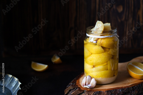 Картината върху платно Fermented lemons in a glass jar on a dark table and dark background