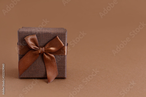 Brown gift box with a bow on a brown background