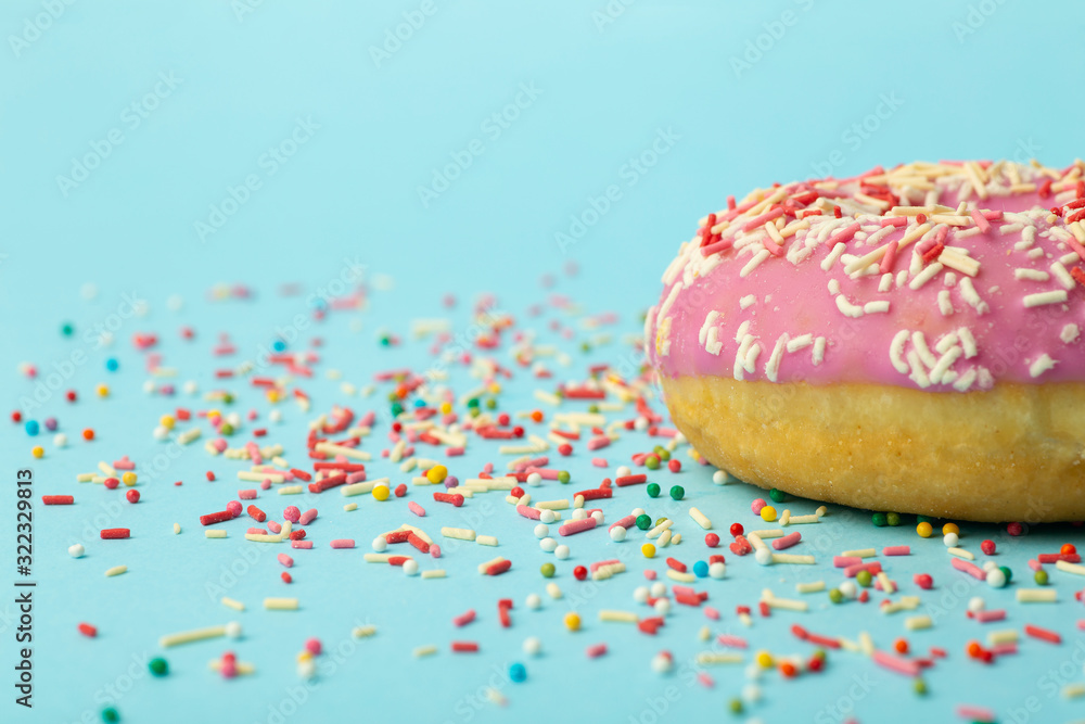 Donut (doughnut) of different colors on a blue background with multi-colored festive sugar sprinkles. Holiday and sweets, baking for children, sugar concept Donut (doughnut) of different colors on a blue background with multi-colored festive sugar sprinkles. Holiday and sweets, baking for children, sugar concept