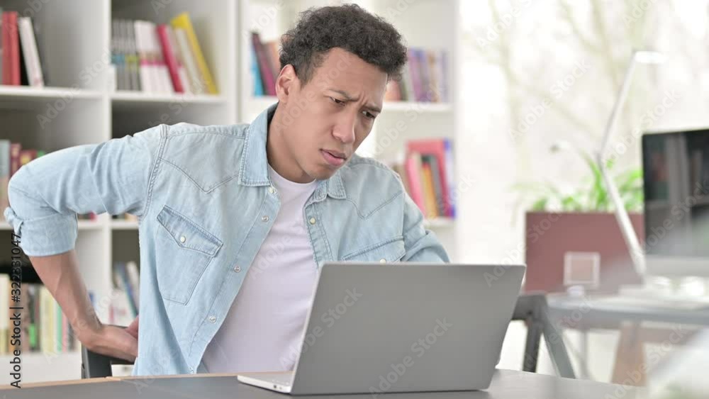Exhausted Young African American Man having Back Pain at Work Exhausted Young African American Man having Back Pain at Work