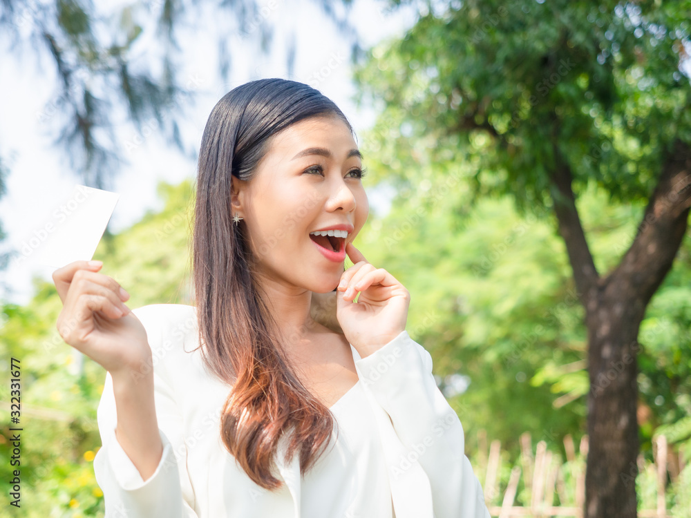 asia happy business woman holding blank card stand in park asia happy business woman holding blank card stand in park
