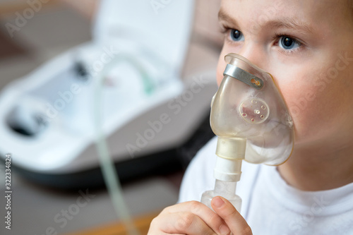 Photography Child makes inhalation at home with nebulizer on out of focus background