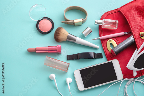Woman fashion bag with cosmetic, accessories and smartphone on blue background