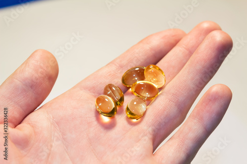 capsules of fish oil lie on a hand on a light background. view from above. vitamins for health.