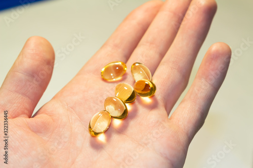 capsules of fish oil lie on a hand on a light background. top view. Vitamins for health.