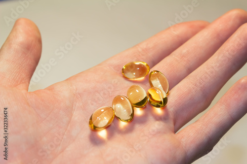 capsules of fish oil lie on a hand on a light background. top view. Vitamins for health.