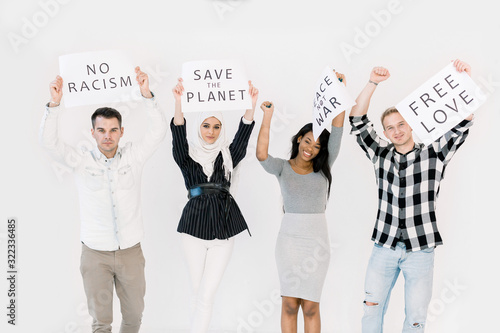 Group of young multiracial people posing together for protesting demonstration, holding posters with antiwar, justice, peace, save the planet, no racism concept photo