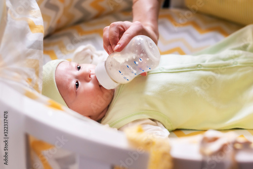 young mother feeds her baby milk from a bottle
