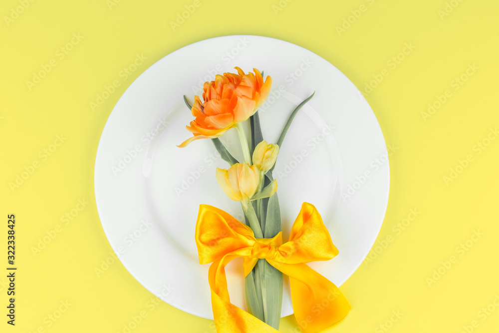 Beautiful yellow tulips in round plate on yellow background. Minimal concept