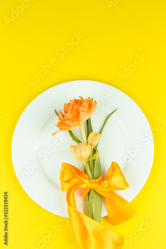 Beautiful yellow tulips in round plate on yellow background. Minimal concept
