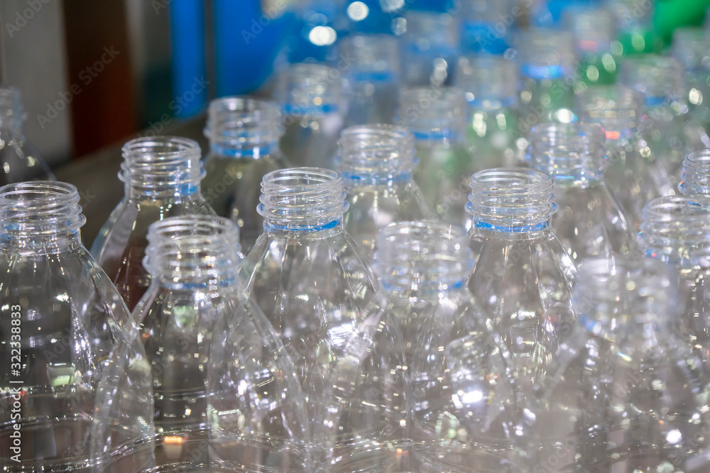 The PET bottles in the rail on the conveyor belt for filling process in the drinking water factory. The drinking water factory production process by automatic filling machine in the plant. The PET bottles in the rail on the conveyor belt for filling process in the drinking water factory. The drinking water factory production process by automatic filling machine in the plant.