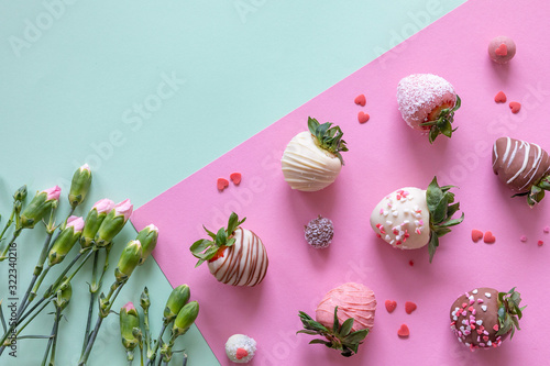 Handmade chocolate covered strawberries and flowers on colored background with free space for text