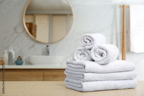 White towels on wooden table in bathroom. Space for text