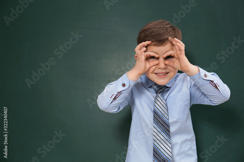 Funny little child near chalkboard, space for text. First time at school