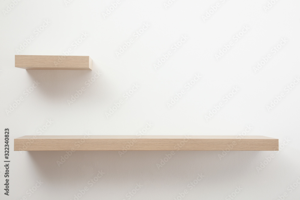 Empty stylish wooden shelves on light wall Empty stylish wooden shelves on light wall