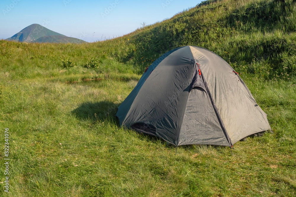 Green tourist tent in camp among meadow in the mountain.Nature background