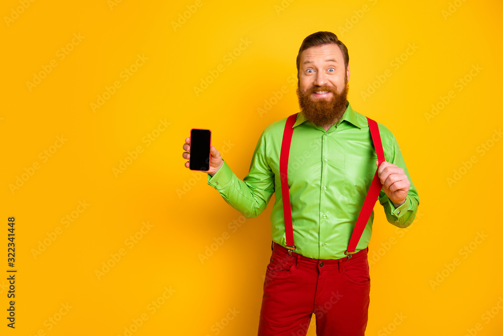 Portrait of cheerful man hold smartphone new modern technology product recommend promo pull stylish suspenders wear good look clothes isolated over yellow color background Portrait of cheerful man hold smartphone new modern technology product recommend promo pull stylish suspenders wear good look clothes isolated over yellow color background