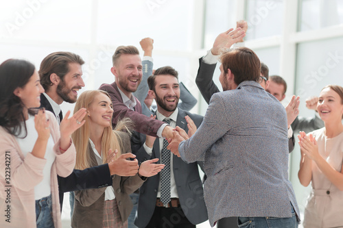 corporate group of employees congratulating their colleague.