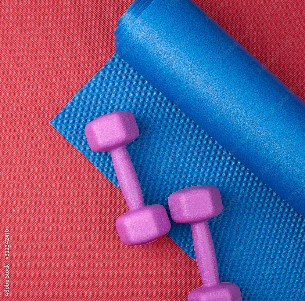pair of purple plastic dumbbells on a blue neoprene mat pair of purple plastic dumbbells on a blue neoprene mat