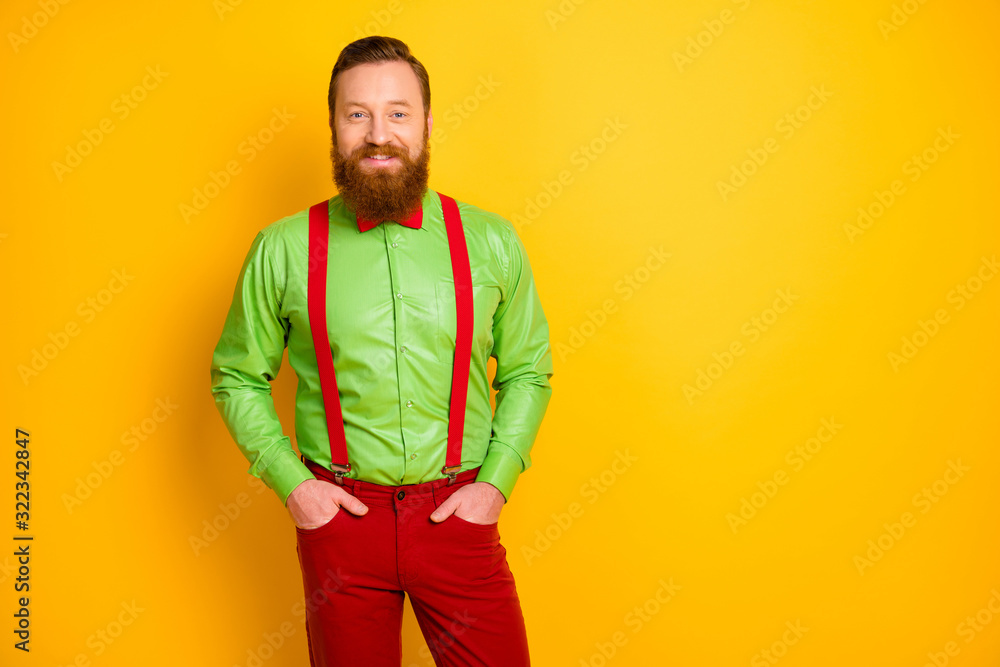 Photo of excited happy red head guy toothy smiling elegant look came party wear bright green shirt red suspenders bow tie trousers isolated yellow color background Photo of excited happy red head guy toothy smiling elegant look came party wear bright green shirt red suspenders bow tie trousers isolated yellow color background