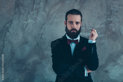 Portrait of his he nice attractive well-dressed serious experienced focused bearded guy wearing tux thinking isolated over gray concrete industrial wall background