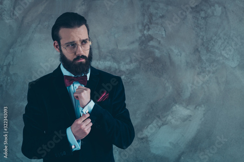 Portrait of his he nice attractive well-dressed classy bearded guy wearing tux fixing cuffs preparing for solemn event isolated over gray concrete industrial wall background