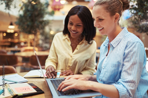 Smiling businesswomen working on a laptop in an office lounge