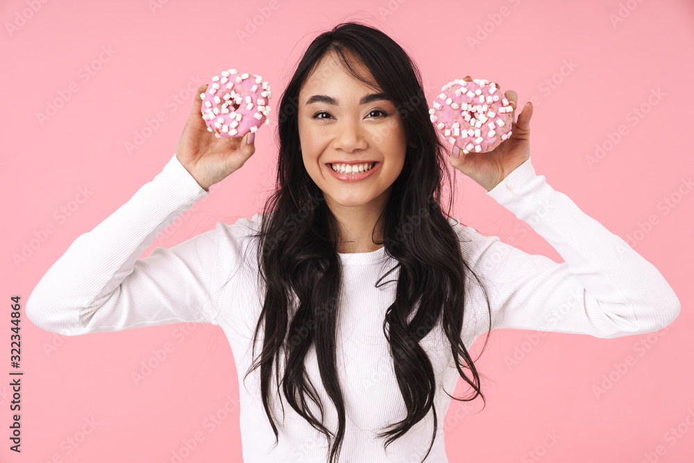Image of young brunette asian woman smiling and holding donuts Image of young brunette asian woman smiling and holding donuts