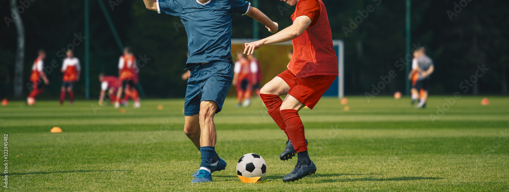 Two Men Kicking Soccer Ball. Junior Teenage Soccer Team on Training Game. Athletes Running with Ball on Football Pitch. Young Soccer Players in Action Two Men Kicking Soccer Ball. Junior Teenage Soccer Team on Training Game. Athletes Running with Ball on Football Pitch. Young Soccer Players in Action