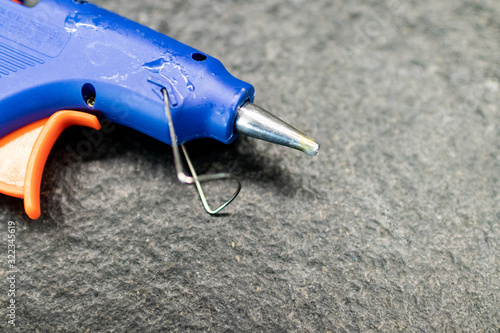 blue hot glue gun dirty with used glue on a black granite table. work table with hot glue gun symbol of creative and educational activities in the field of making and technology photo