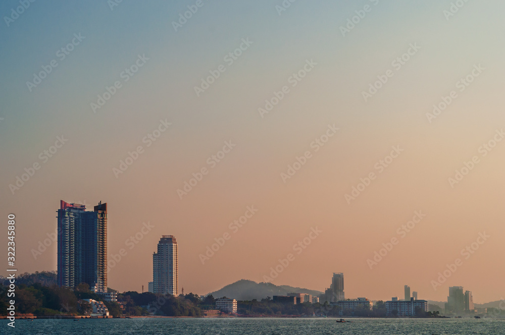 The buildings and skyscrapers on the sea shore in dramatic blue and red sky, minimalist view from the sea.