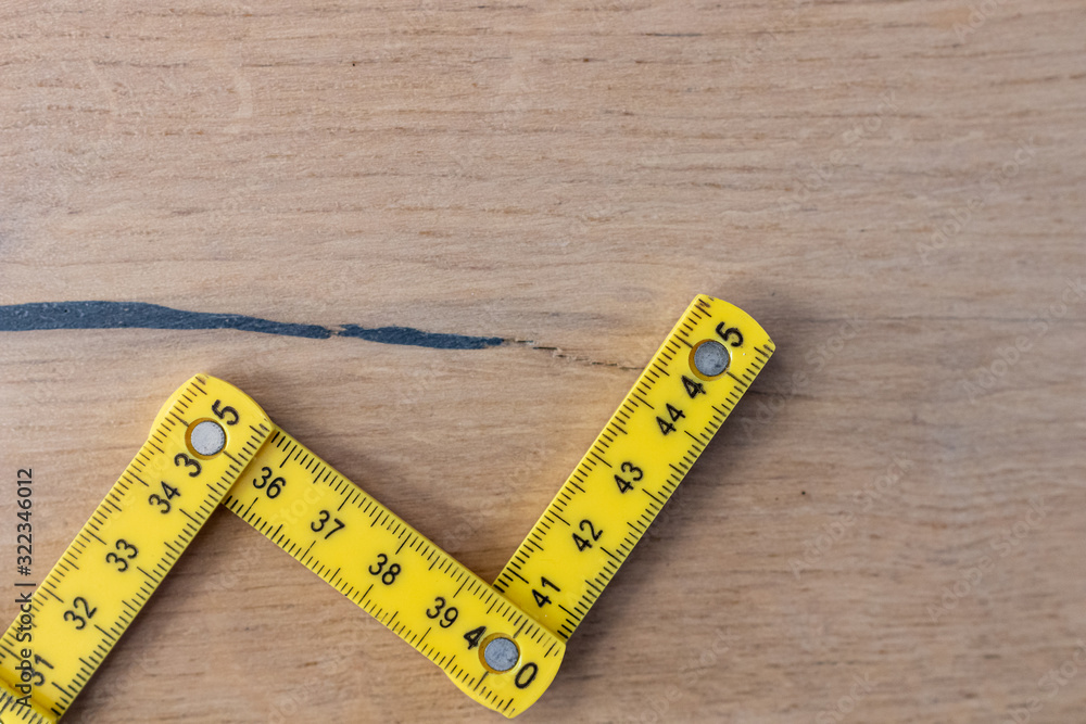 Folding zig zag ruler. Measuring tape folding yellow open in zigzag tips on a workbench. Measuring tools for carpenters and bricklayers. Measurement for building renovations of houses and apartments Folding zig zag ruler. Measuring tape folding yellow open in zigzag tips on a workbench. Measuring tools for carpenters and bricklayers. Measurement for building renovations of houses and apartments
