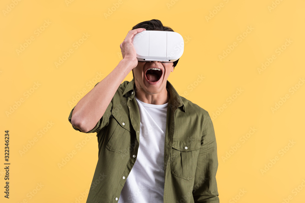 excited young man yelling while using virtual reality headset, isolated on yellow excited young man yelling while using virtual reality headset, isolated on yellow