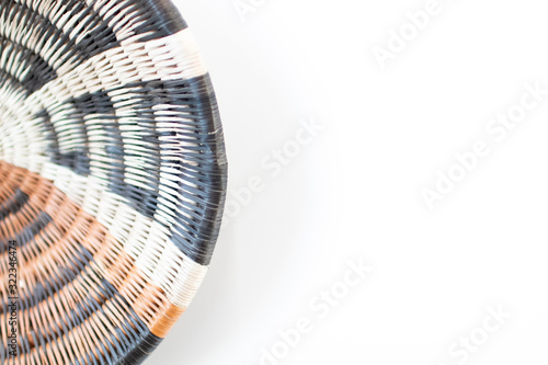 handcrafted wicker basket colored with ethnic and African earth colors on a white background. Detail of a circular straw bowl decorated with ethnic motifs. African handmade craftsmanship example set