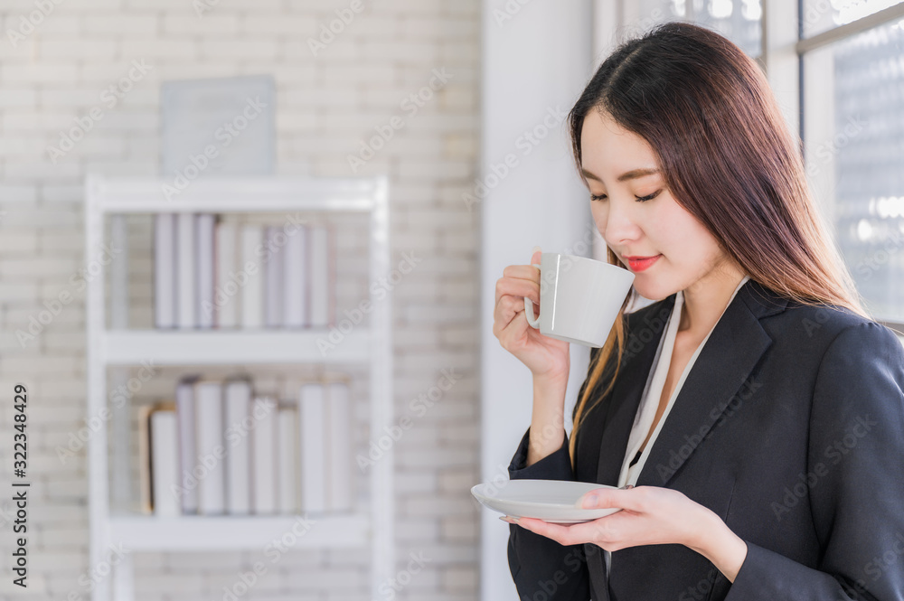 Beautiful young asian businesswoman in suit standing holding white coffee cup Beautiful young asian businesswoman in suit standing holding white coffee cup