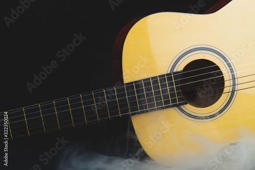 Acoustic guitar in smoke on the black background. musical instrument