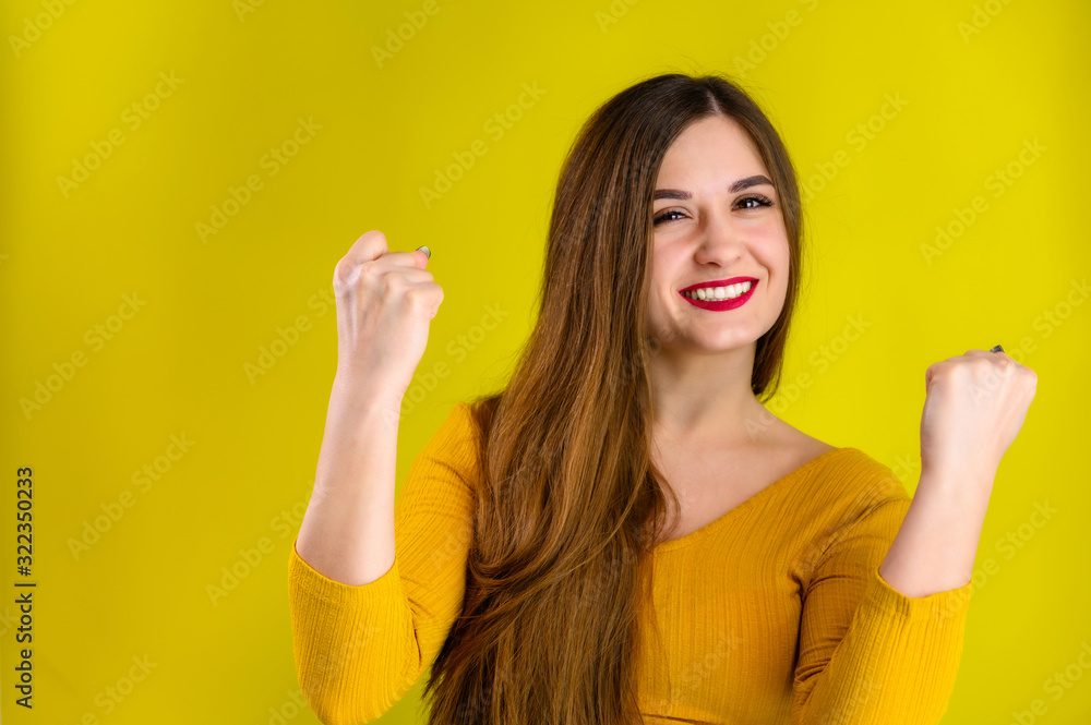 nice brunette girl with long hair with a smile in a yellow jacket rejoices on a yellow background, smiles and shows positive emotions nice brunette girl with long hair with a smile in a yellow jacket rejoices on a yellow background, smiles and shows positive emotions