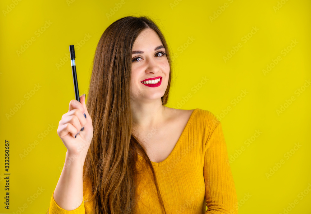 nice brunette girl with long hair with a smile with a pen in her hands in a yellow sweater is happy over a yellow background smiling and showing positive emotions nice brunette girl with long hair with a smile with a pen in her hands in a yellow sweater is happy over a yellow background smiling and showing positive emotions