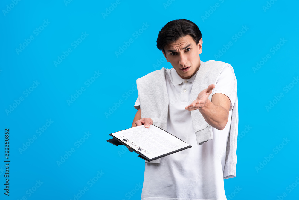 irritated man holding clipboard with contract, isolated on blue irritated man holding clipboard with contract, isolated on blue