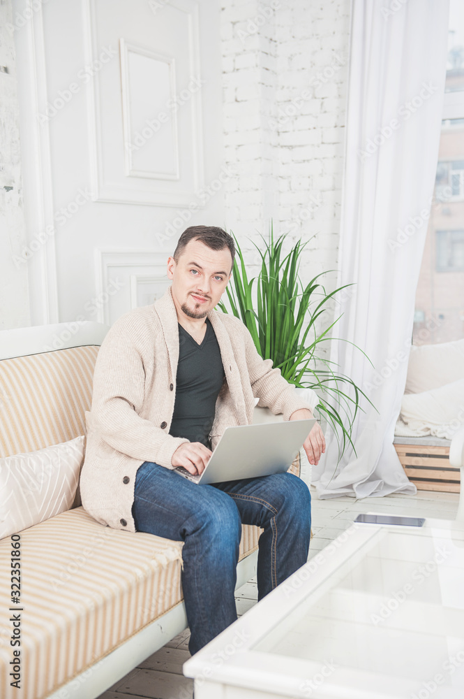 Handsome happy man working using laptop on the couch at home Handsome happy man working using laptop on the couch at home