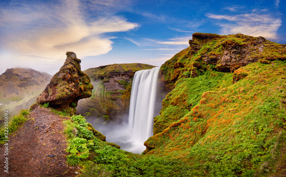 Panoramic view of Skogafoss waterfall on the Skoga river, a popular tourist attraction and part of the Golden Circle Tourist Route. Famous landmark of Iceland, Europe. Travelling concept background. Panoramic view of Skogafoss waterfall on the Skoga river, a popular tourist attraction and part of the Golden Circle Tourist Route. Famous landmark of Iceland, Europe. Travelling concept background.